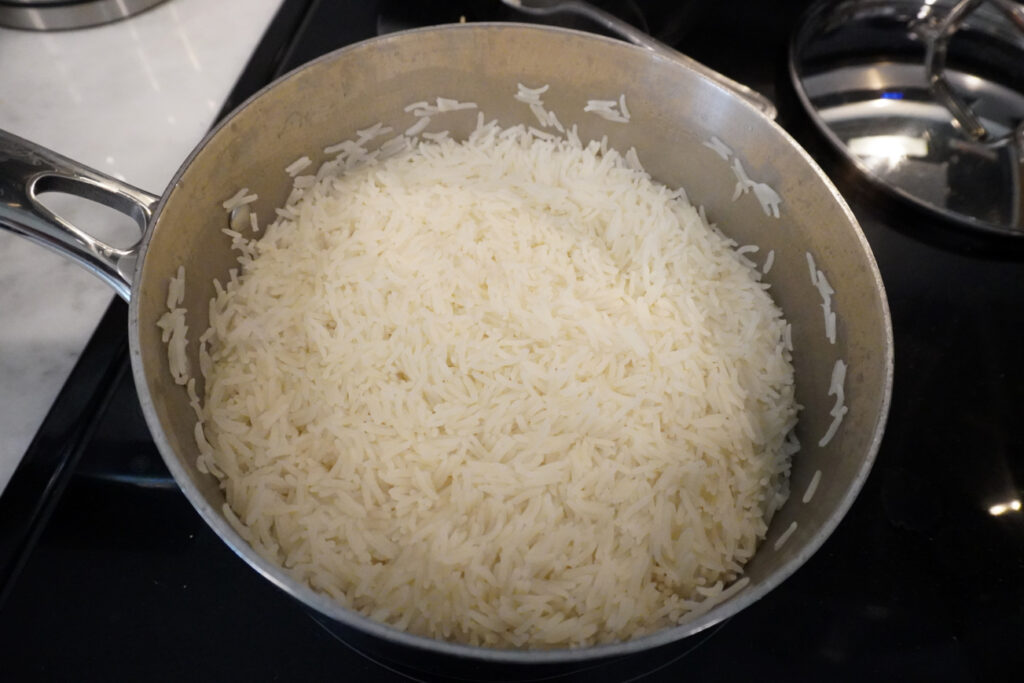cooked basmati rice in a stainless steel pot on a black stove