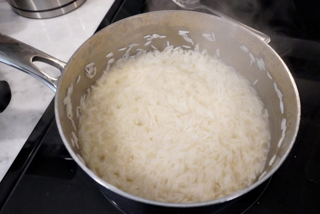 a pot of rice on the stove halfway through cooking