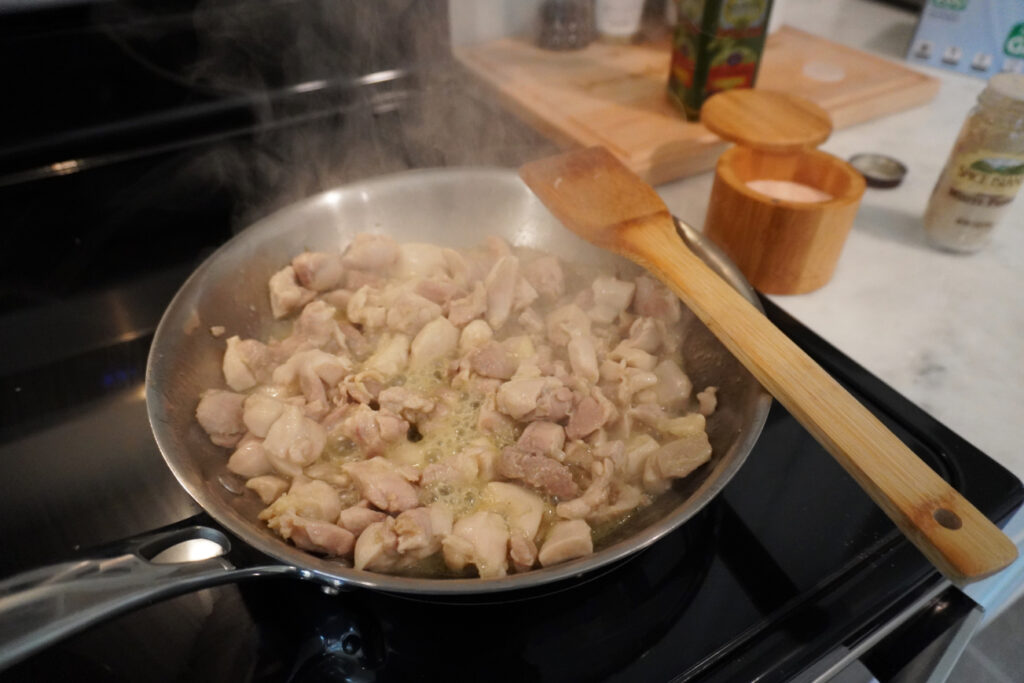 a pan of cubed chicken cooking on the stove 