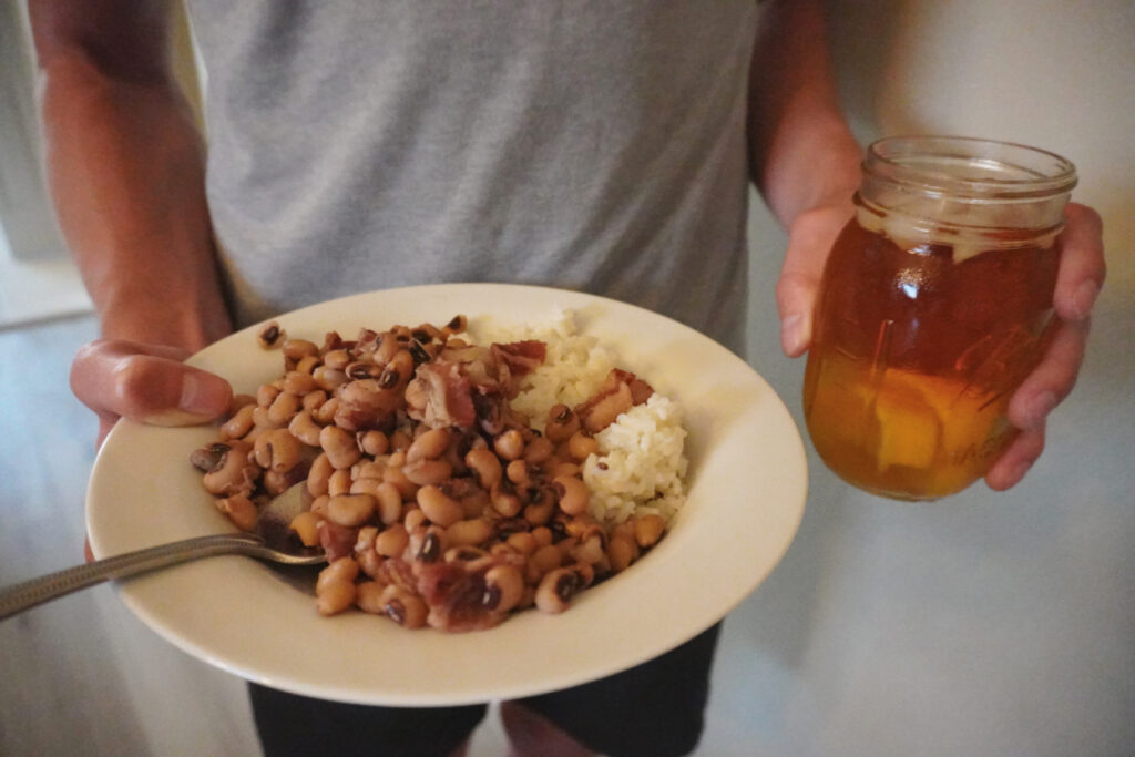 man holding a plate of black eyed peas and rice and a glass of sweet tea