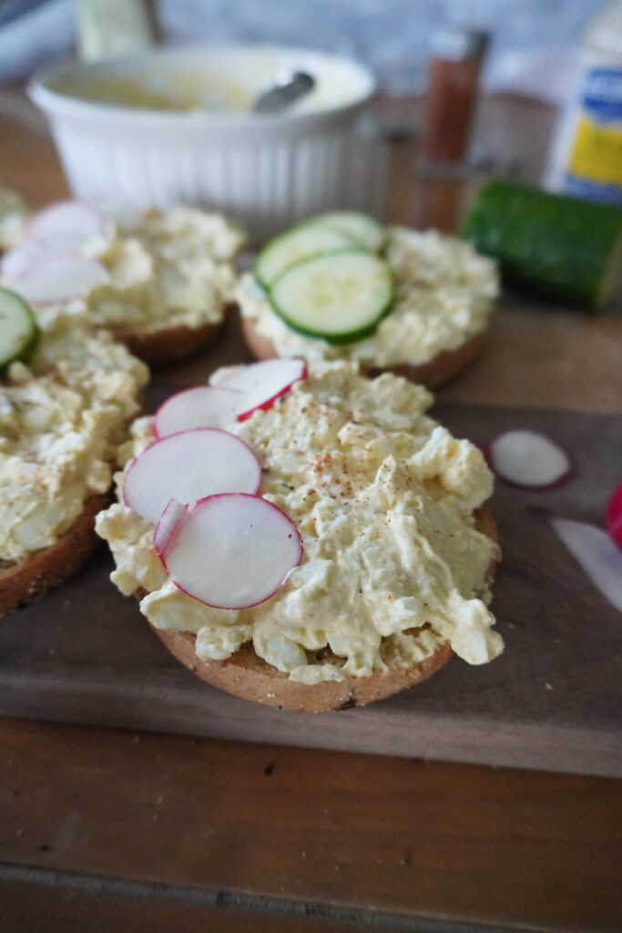 bagels topped with egg salad, radishes, and cucumbers