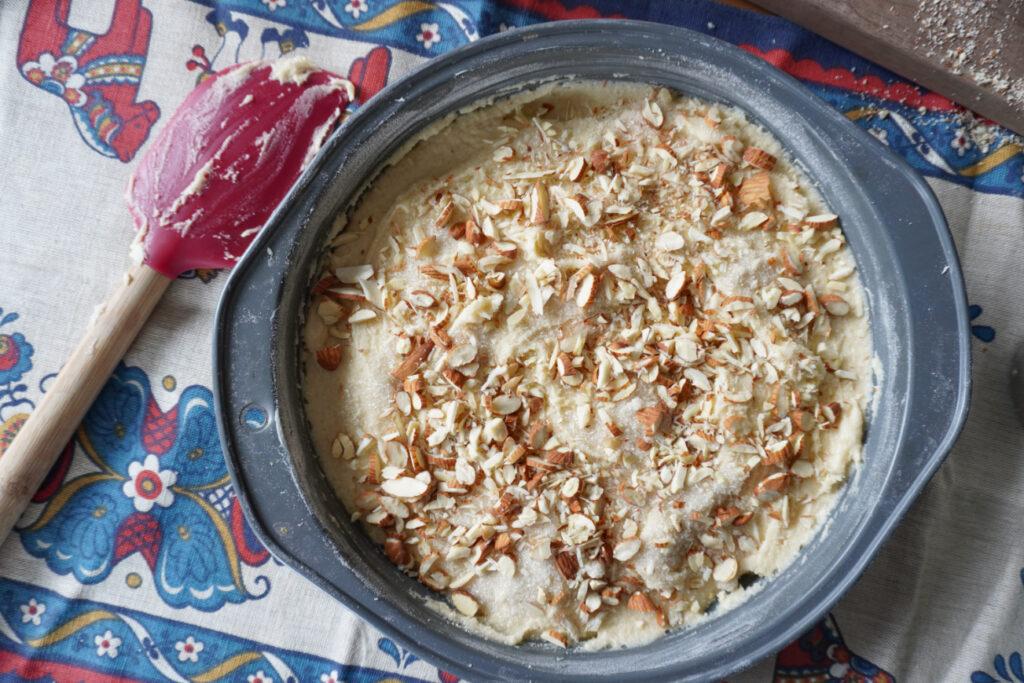 a pan of almond skillet cake batter topped with almonds and granulated sugar