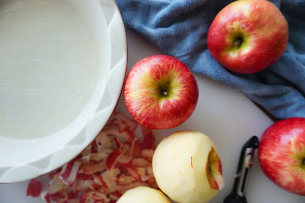 apples alongside a buttered pie dish