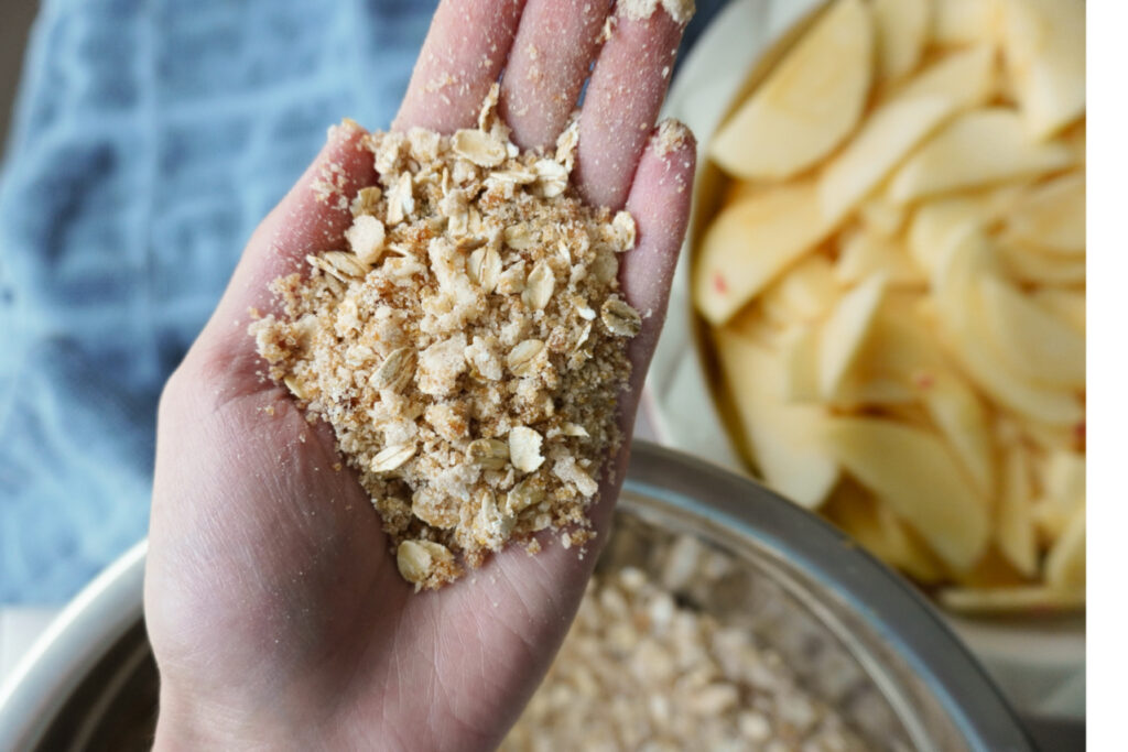 a hand holding a handful of the topping mixture for an apple crisp
