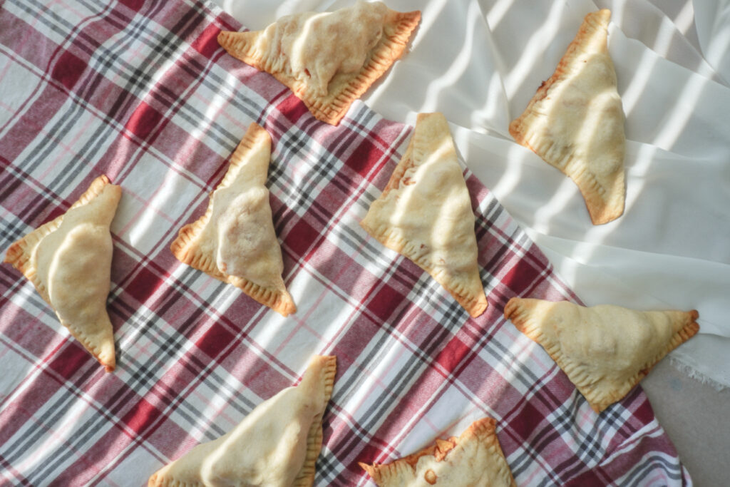 Apple turnovers arranged on a white background and red flannel background with sun light casting on them