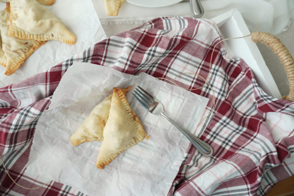 two apple turnovers served in a white tray with a red flannel background