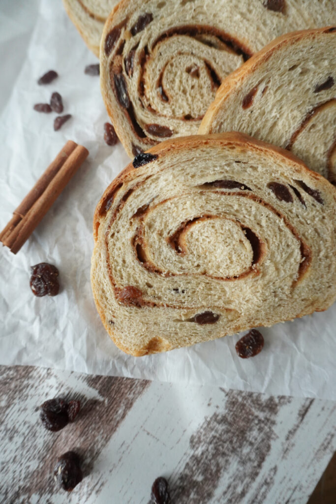 slices of cinnamon raisin bread with cinnamon sticks and raisins arranged around them