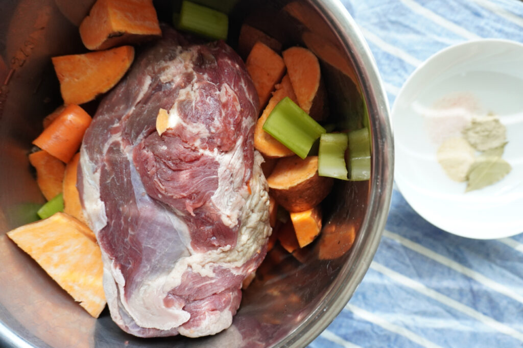 raw chuck roast with sweet potatoes, carrots, and celery in an Instant Pot