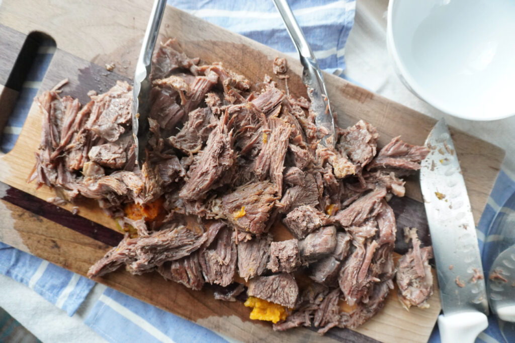 shredded pot roast on a cutting board