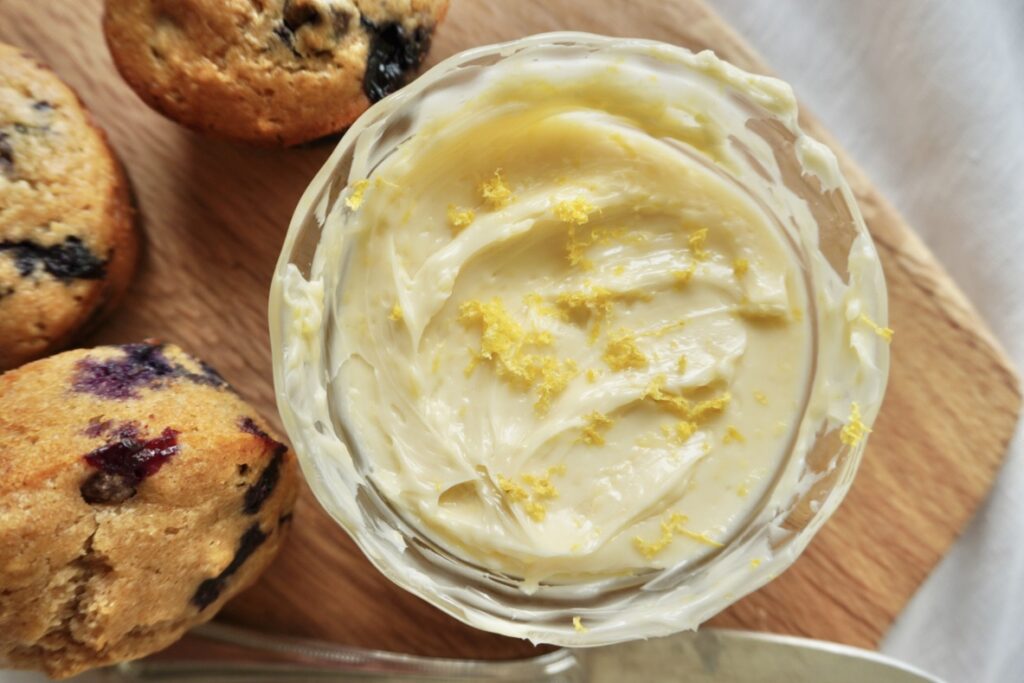 a dish of bright yellow whipped lemon honey butter topped with lemon zest