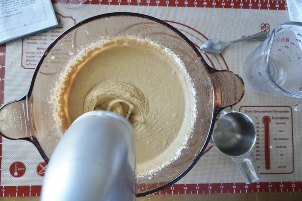an electric mixer beating the brown bread sponge