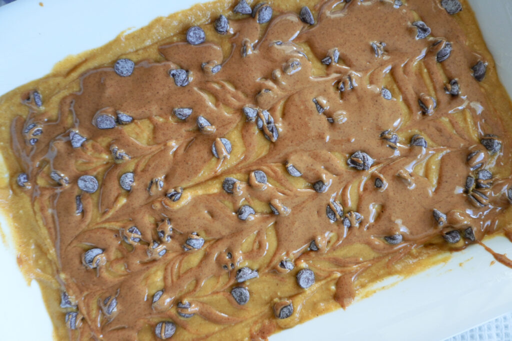 a 9x13 of pumpkin bar batter topped with almond butter and chocolate chips