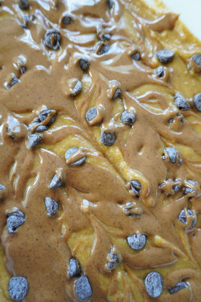 almond butter and chocolate chips on top of pumpkin bar batter
