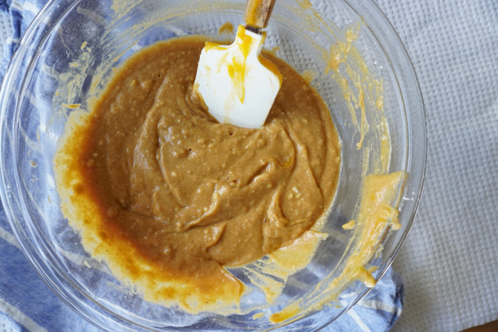 a mixing bowl of pumpkin bar batter with a rubber spatula 