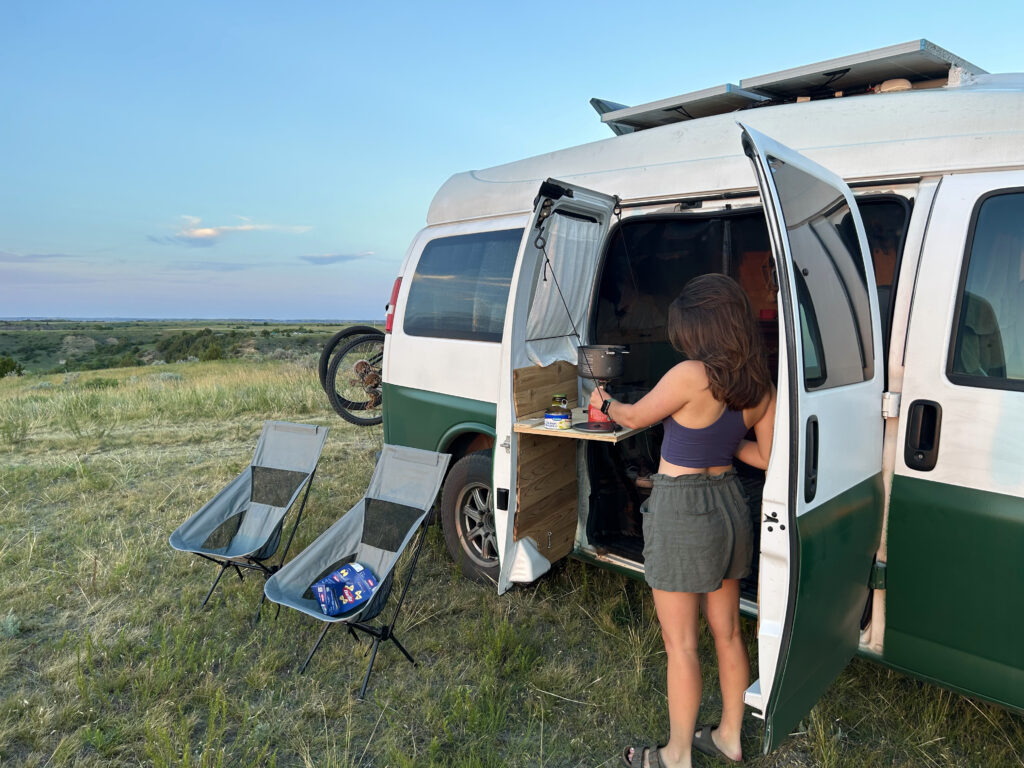 a woman making food outdoors in a camper van